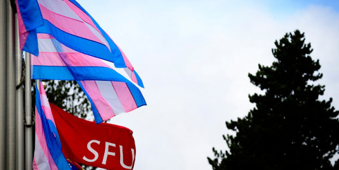The trans and SFU flags flying together at Burnaby campus.